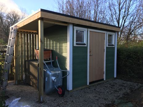Litet grönt trähus med ljus dörr
