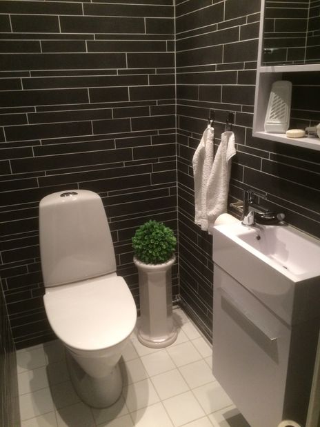 Badrum med svart schiffervägg, blomma, vitt handfat