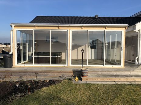Uterum i glas på en trädäckad altan, svart jacuzzi under tak.