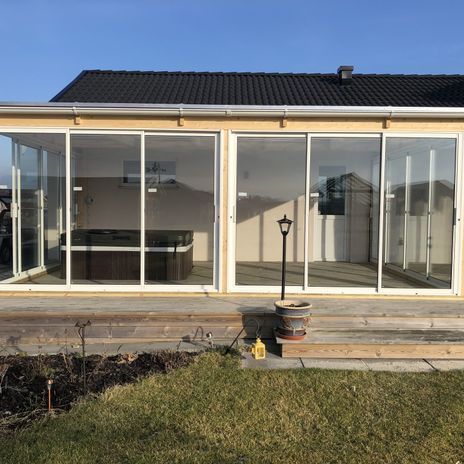 Uterum i glas på en trädäckad altan, svart jacuzzi under tak.