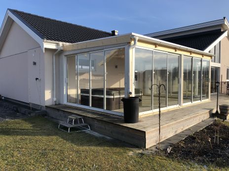 Uterum i glas på en trädäckad altan, svart jacuzzi under tak.